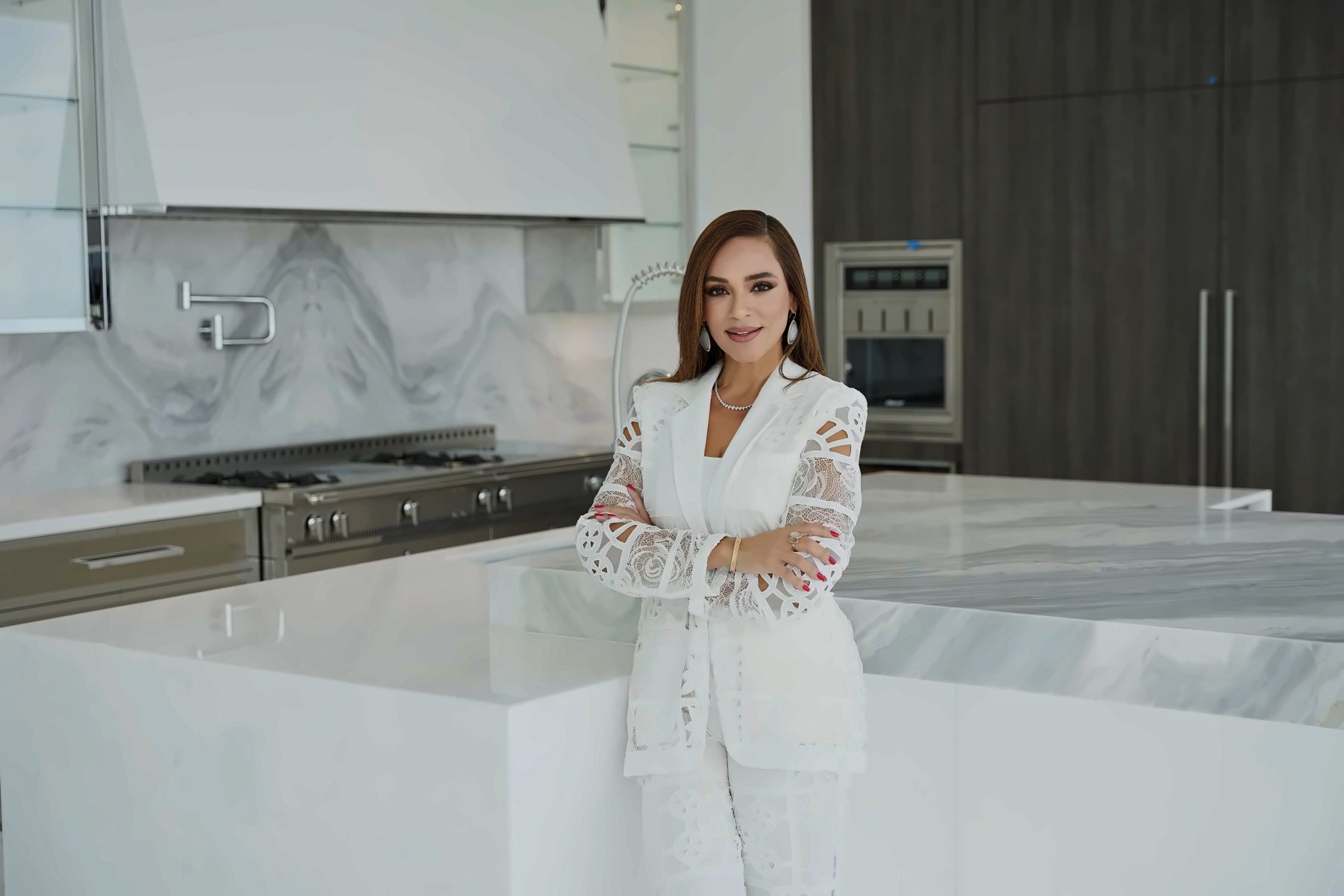 Agent in a white suit leaning on a marble kitchen island
